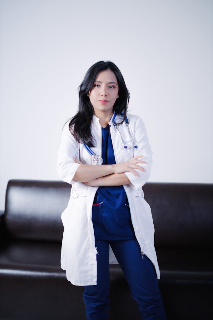 A confident female doctor with crossed arms standing in a medical office, exuding professionalism.